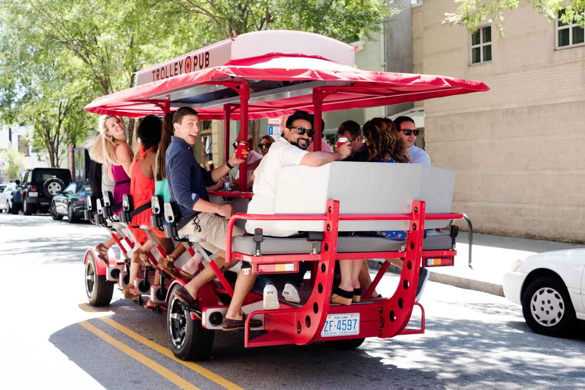 Group of people enjoying a ride on a pedal-powered trolley pub in a city setting