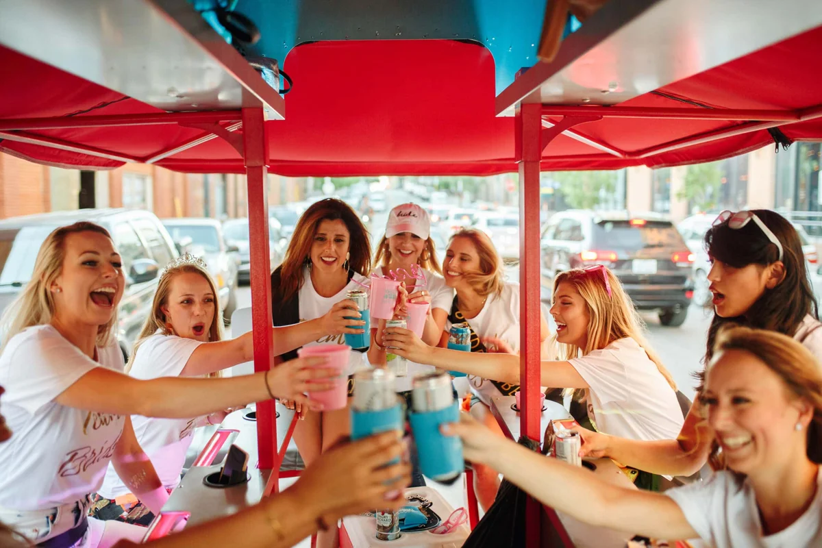 Group of friends celebrating with drinks on a party bike outdoors