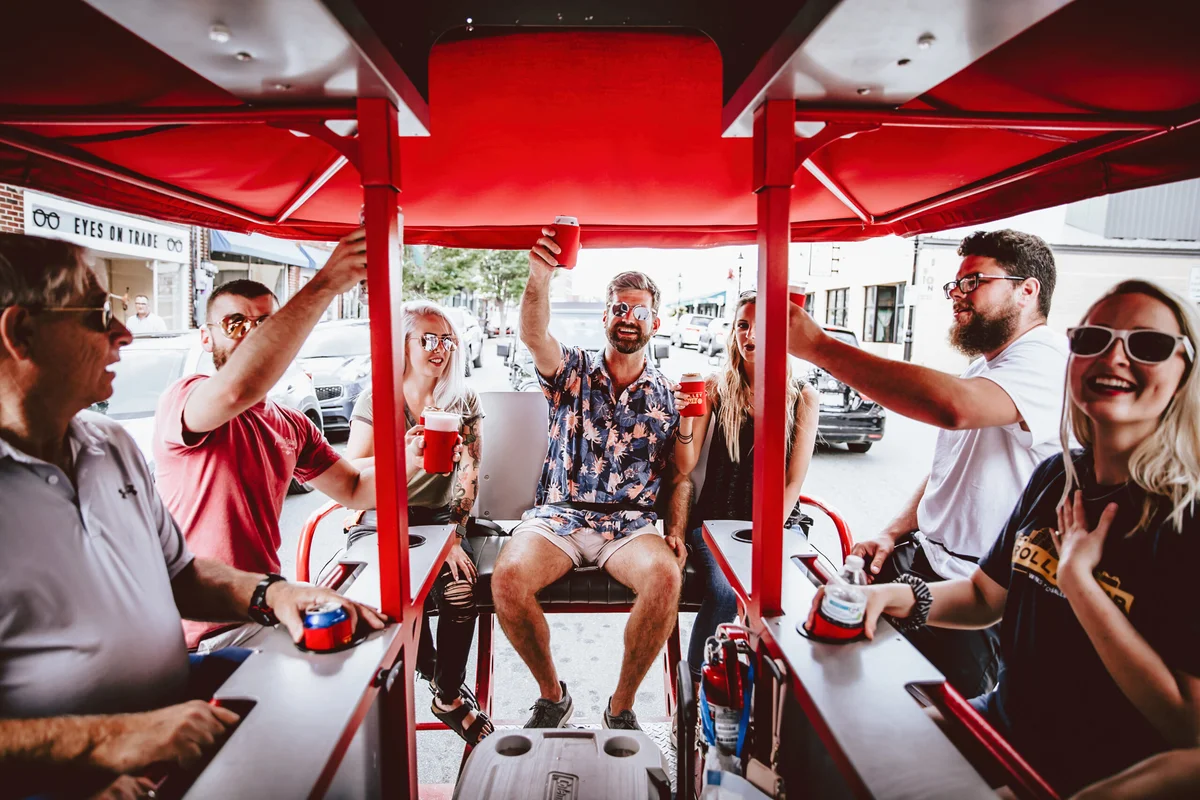Group of people enjoying a social ride on a beer bike in an urban setting