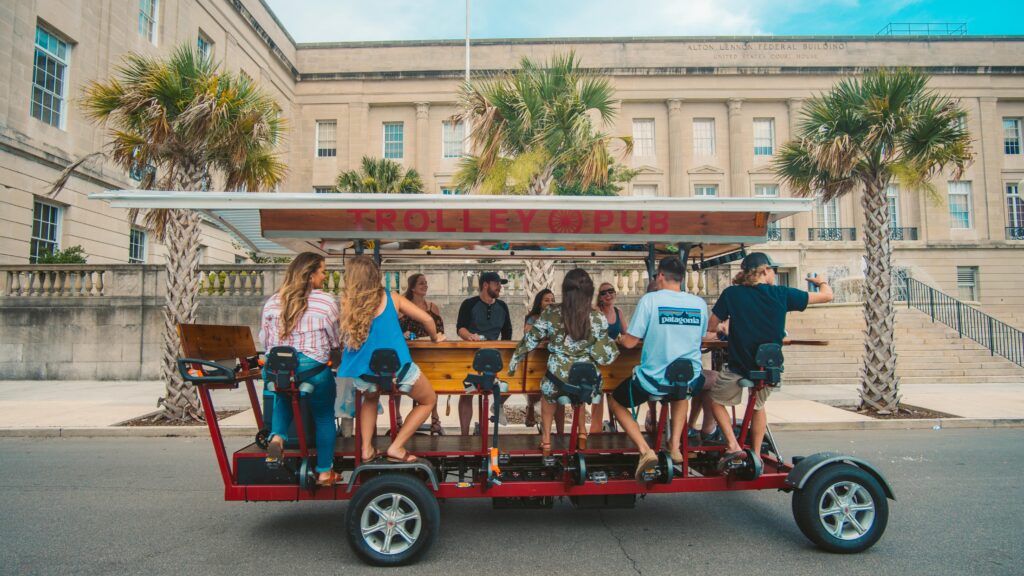 A pedal-powered trolley pub with passengers on a street.