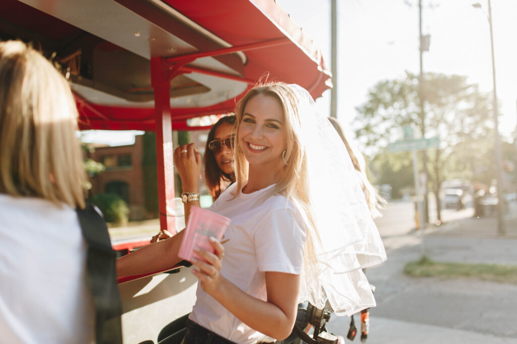 People at an outdoor food stand with a sunny street backdrop.