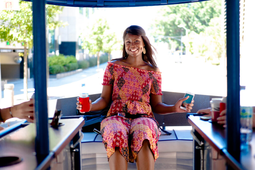 A person in a colorful outfit sitting at a table with a drink, holding a smartphone.