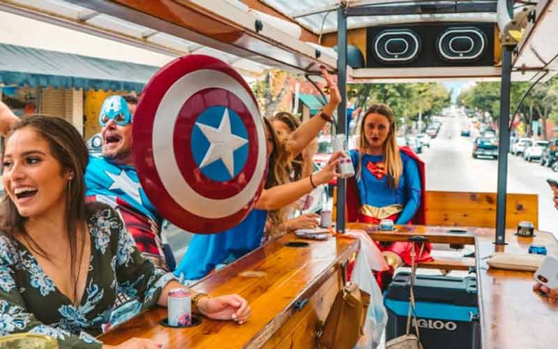 People in superhero costumes enjoying a lively ride on a party bus. People dressed in superhero costumes having fun on an open-air party bus.